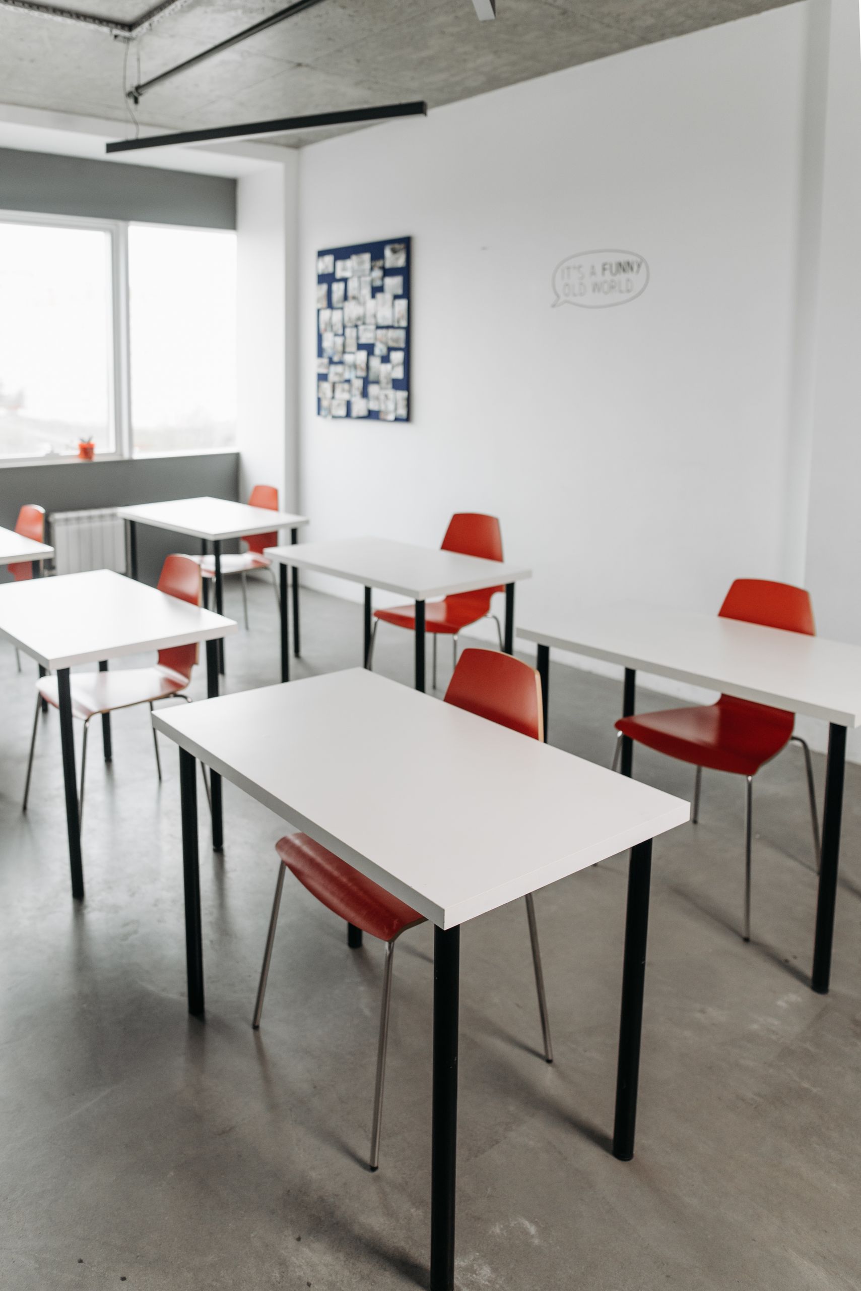 Contemporary classroom interior with red chairs and white desks arranged in rows.
