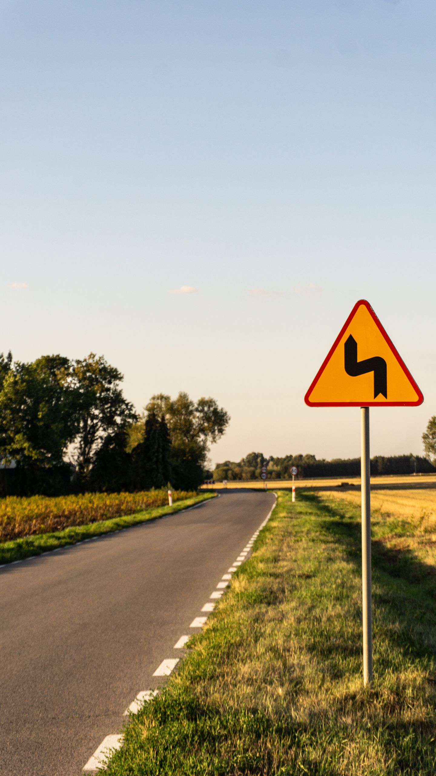 Empty countryside road with warning sign under a golden sunset in Warsaw, Poland.